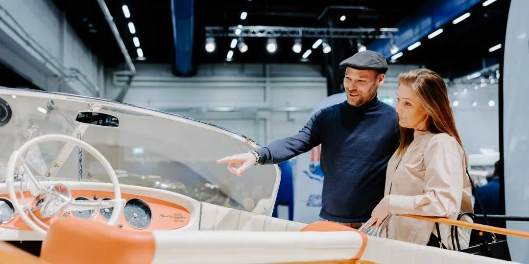 Par betraktar elegant orangevit båt, mannen pekar