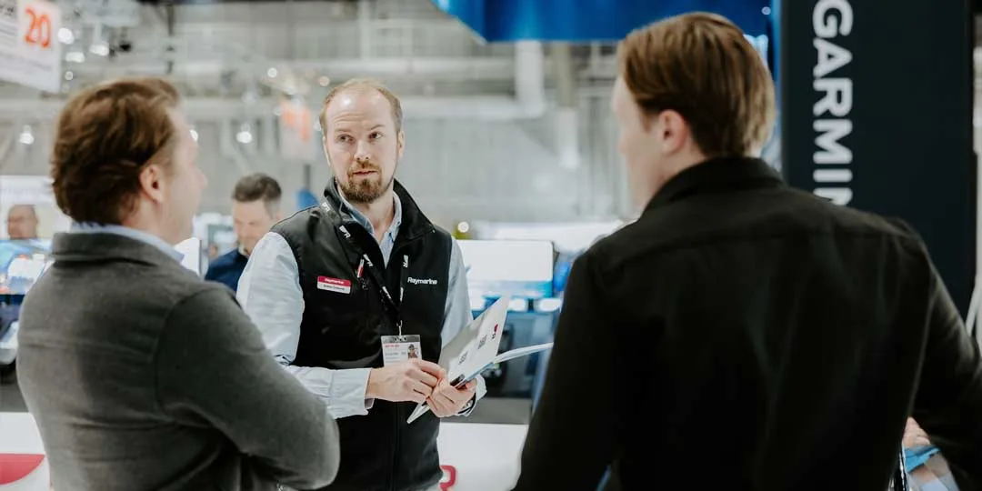 En försäljare från Raymarine samtalar med två besökare.