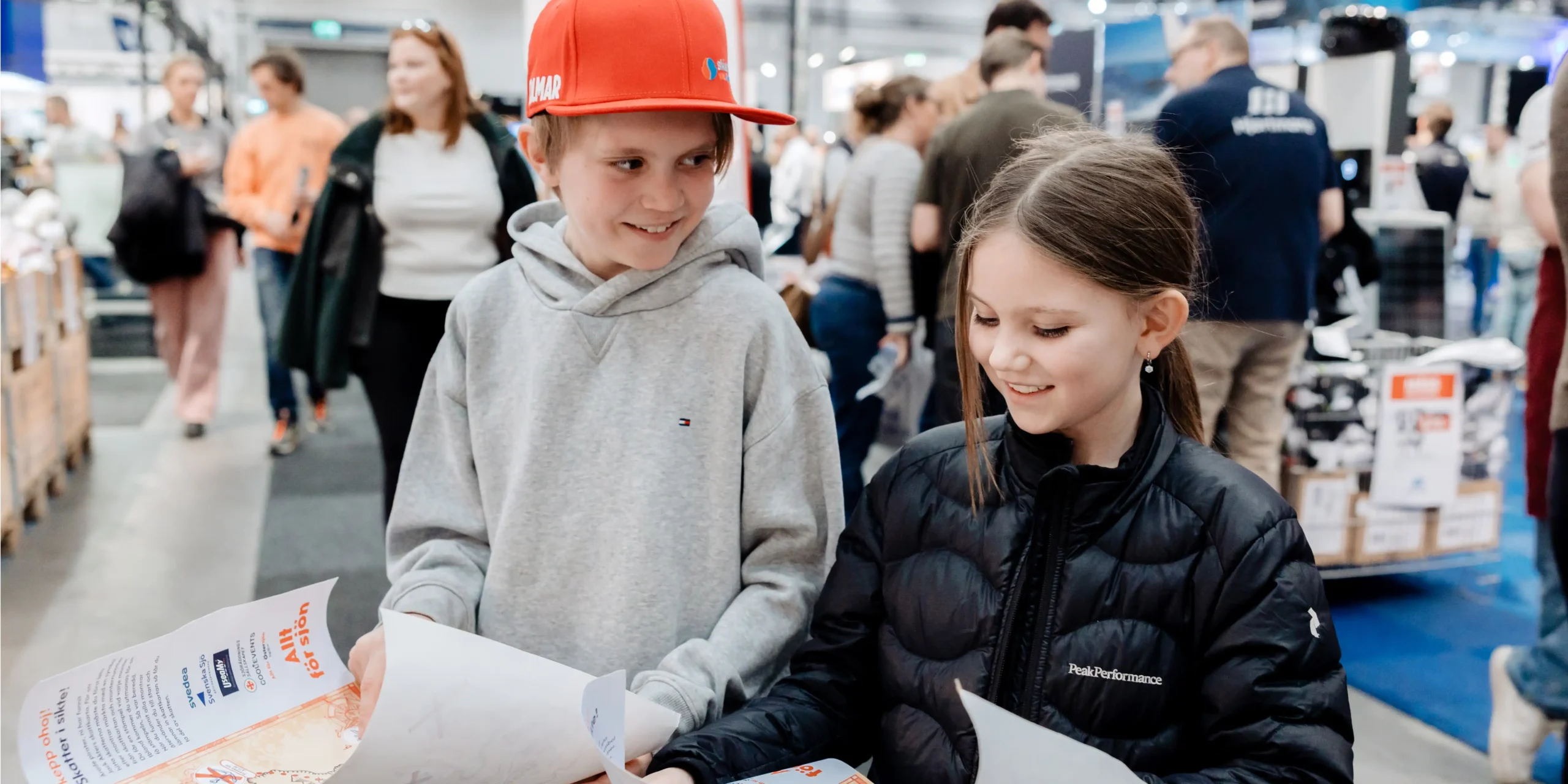 Kul-for-barnen_1080x540 Två barn ler och tittar på kartor under sitt besök på mässan Allt för sjön.